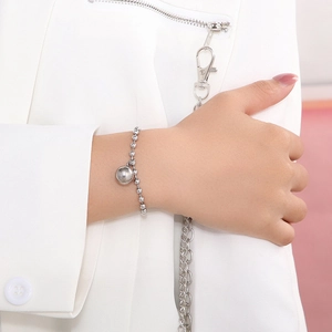 Close-up of silver hollow bead bracelet with small sphere pendant on model wrist