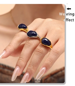 Detail of a vintage 18k gold plated ring with blue resin stones worn on multiple fingers