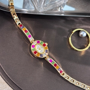 Detailed view of women's quartz watch with gold metal band and colorful zircon gemstones