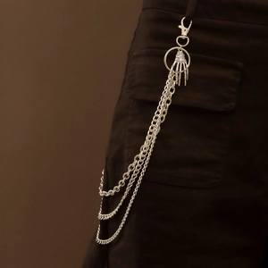 Detail of silver multi-layer metal pants chain with skull hand pendant on denim