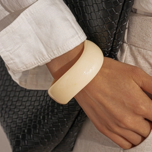 Minimalist wide creamy white acrylic bangle styled with white linen and black leather bag