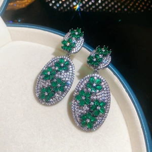 Macro shot of silver zircon flower earrings with green stones in a velvet jewelry box