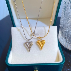Dual gold and silver heart pendants on beaded snake chains presented in a green gift box