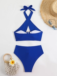 Flat lay of navy blue halter bikini set with high waist bottom and resort accessories