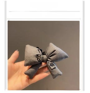 Detailed macro view of gray fabric bow hairband with rhinestones and metal charm logo