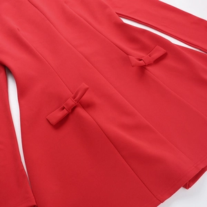 Dettaglio dell'abito rosso con due eleganti fiocchi coordinati su tessuto di alta qualità