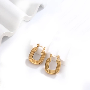 Macro detail of gold U-shaped geometric earrings with textured horizontal stripes