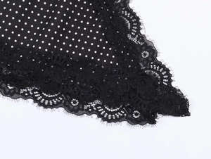 Detailed view of the black fabric with white polka dots and delicate floral lace trim