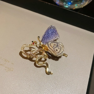 Detailed macro of gold butterfly brooch with purple mesh wing and diamond snake accent