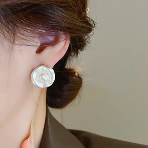 Elegante orecchino a rosa d'argento con perla sull'orecchio di una donna in luce naturale