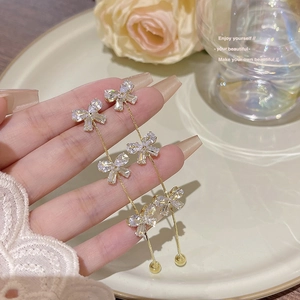Detail view of long gold tassel earrings with three sparkling bow rhinestones for women