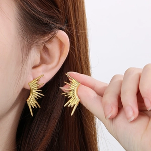 Fashionable 18k gold plated sunburst earrings in stainless steel on a female model