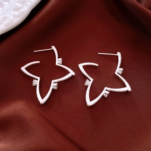 Macro detail of silver star-shaped earrings on elegant pleated dark silk background