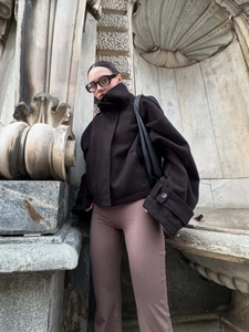 Low-angle street shot of women's black cropped stand-collar wool jacket with bronze pants