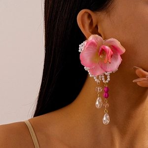 Close-up of pink fabric orchid earrings with pearls and a teardrop crystal drop