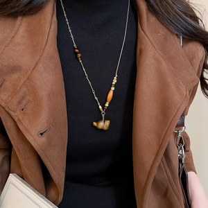 Macro detail of vintage tiger eye gourd pendant on long wood bead and leather necklace