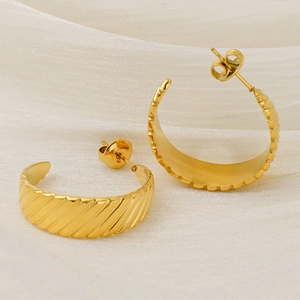 Macro shot of 18K gold plated chunky earrings with diagonal stripes on silk cloth
