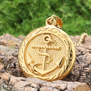 Macro shot of gold anchor pendant with embossed texture on natural tree bark background