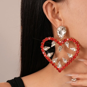 Close-up of heart-shaped drop earrings with red and clear rhinestones on model