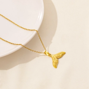 Macro detail of golden mermaid tail pendant with intricate ocean texture and 18K plating