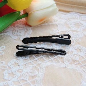 Close-up of black wave-shaped metal hair clips on a delicate lace fabric background