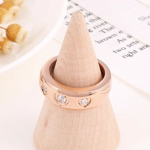 Dettaglio anello a cuore in oro rosa con cristallo su supporto per gioielli in legno