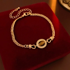 Gold-plated chain bracelet with oval tiger eye stone and crystal halo on red velvet