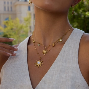 Close-up of layered 18K gold sun moon star pendant necklace set with opal details