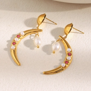 Detail of 18K gold horn-shaped earrings with white pearls and pink gemstones in macro view