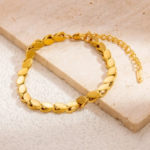 Detailed macro view of gold leaf charm bracelet with S.STEEL engraved tag and extender chain