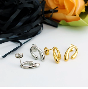 Detailed view of gold and silver horseshoe U-shaped earrings with mirror polish finish