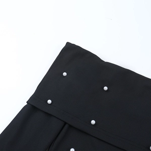 Détail de robe noire en tissu côtelé avec perles blanches et finitions de couture
