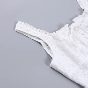 Détail de broderie anglaise blanche avec bretelles à volants et col à cordon