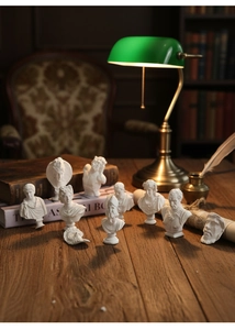Close-up of mini white resin Greek statues on vintage desk with classic library decor