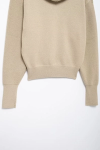 Detailed close-up showing the ribbed hem and soft knit texture of a beige hoodie
