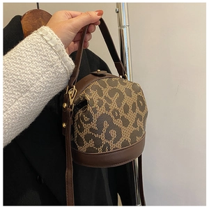 Detail showing the leopard print fabric and leather trim of the vintage bucket handbag