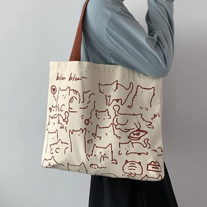 Close-up of cream canvas tote bag featuring a cute hand-drawn brown cat illustration