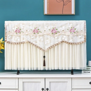 Detail of white lace TV dust cover with pink floral embroidery and hanging tassels