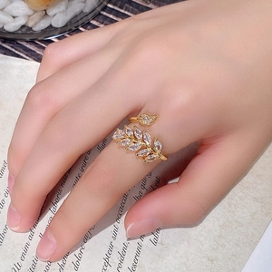 Close-up of sparkling zircon-studded leaf design on a gold adjustable open ring