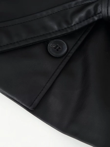 Détail de la veste en similicuir noir présentant des coutures de précision et un bouton à trous