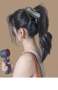 Détail d'une grande pince à cheveux en satin noir sur une demi-queue de cheval élégante