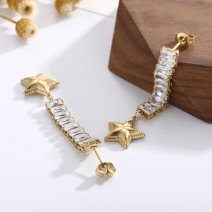 Detail of gold tassel earrings with star element and rectangular zircon stones
