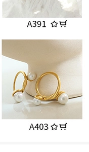 Detailed close-up of two gold rings featuring white freshwater pearls on a ceramic stand