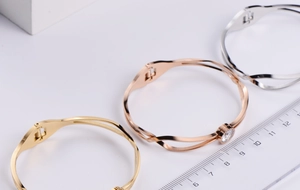Detail view of twisted titanium steel bangles in gold, rose gold and silver with zircon