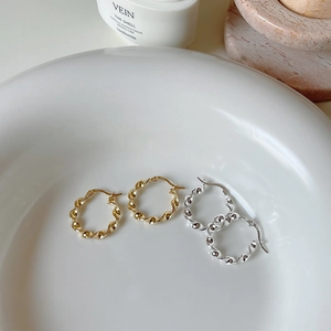 Macro detail of twisted textured hoop earrings in gold and silver 925 silver finish