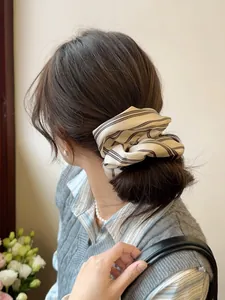 Detail of cream striped scrunchie on a ponytail showing soft pleated chiffon fabric