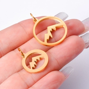 Hollow round mountain peak pendants in gold stainless steel held for size comparison