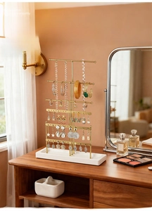 Detail of a gold metal jewelry rack with multiple bars on a vanity for necklace storage