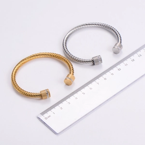 Detailed view of gold and silver twisted cable bangles measured with a metric ruler