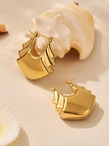 Détail de boucles d'oreilles dorées géométriques avec un design à plusieurs étages